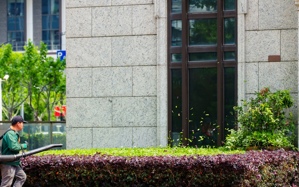 A groundskeeper clearing a planted border outside a commercial building