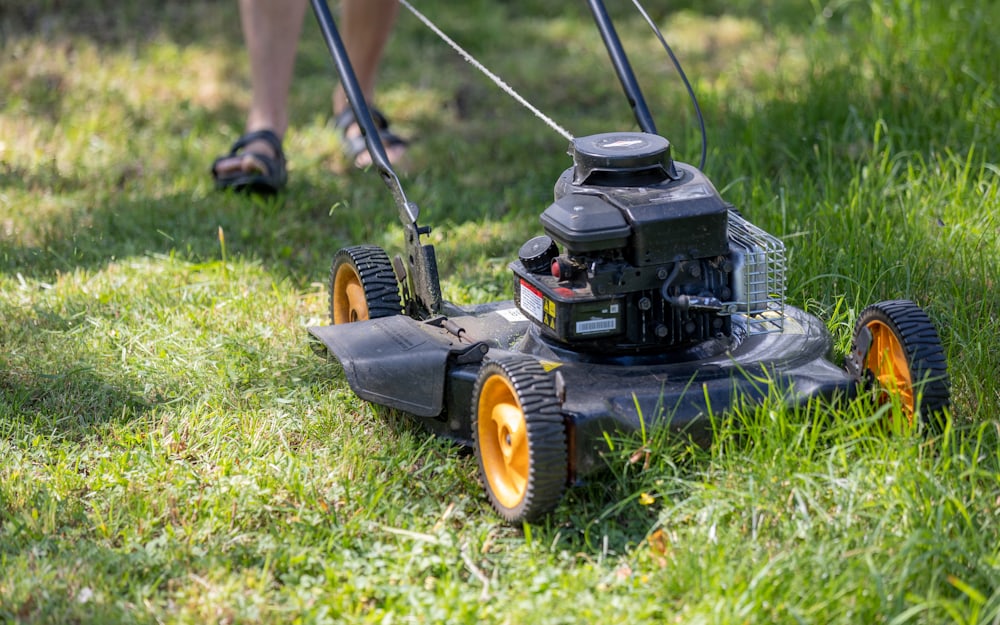 A walk-behind mower cutting a healthy green lawn