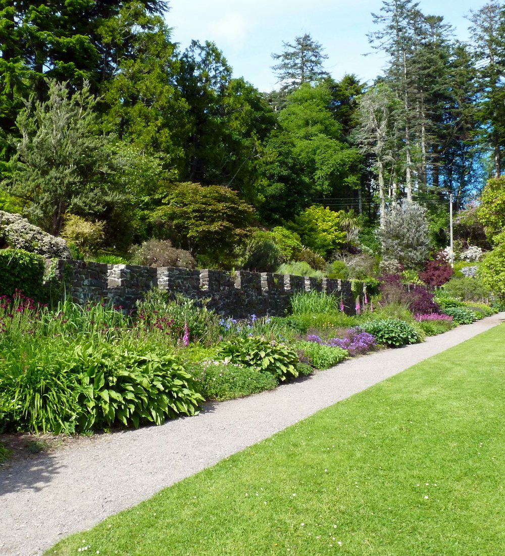 A mown lawn beside a gravel path and a deep planted border